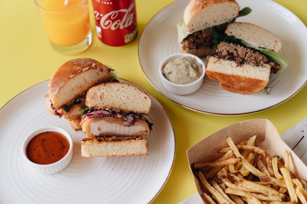 A mouthwatering display of burgers, fries, and drinks on a bright yellow surface.